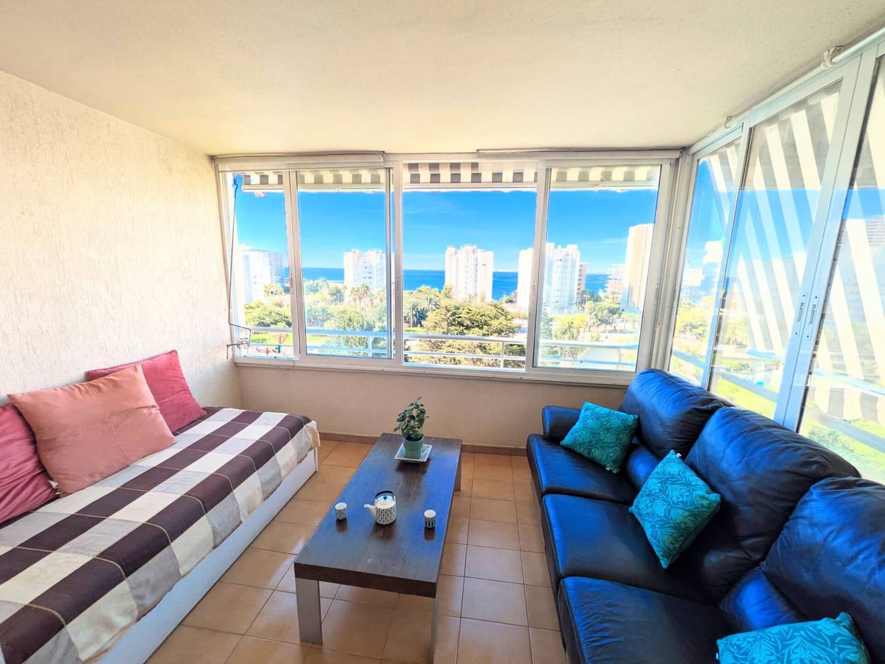 Balcon vitré avec canapés face à la mer, aux jardins et à la piscine