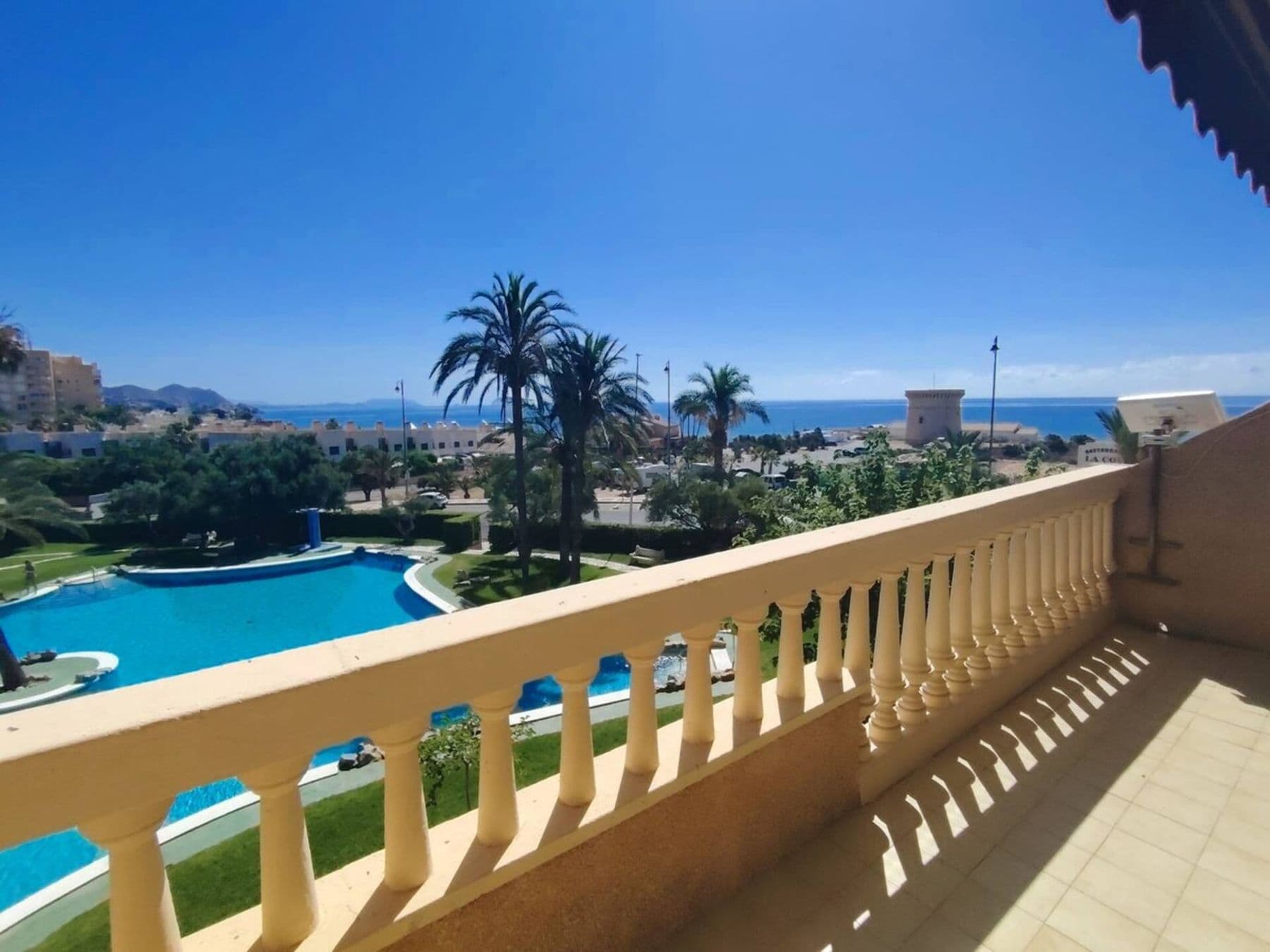 Terrasse ensoleillée avec vue sur la piscine, les palmiers et la Méditerranée