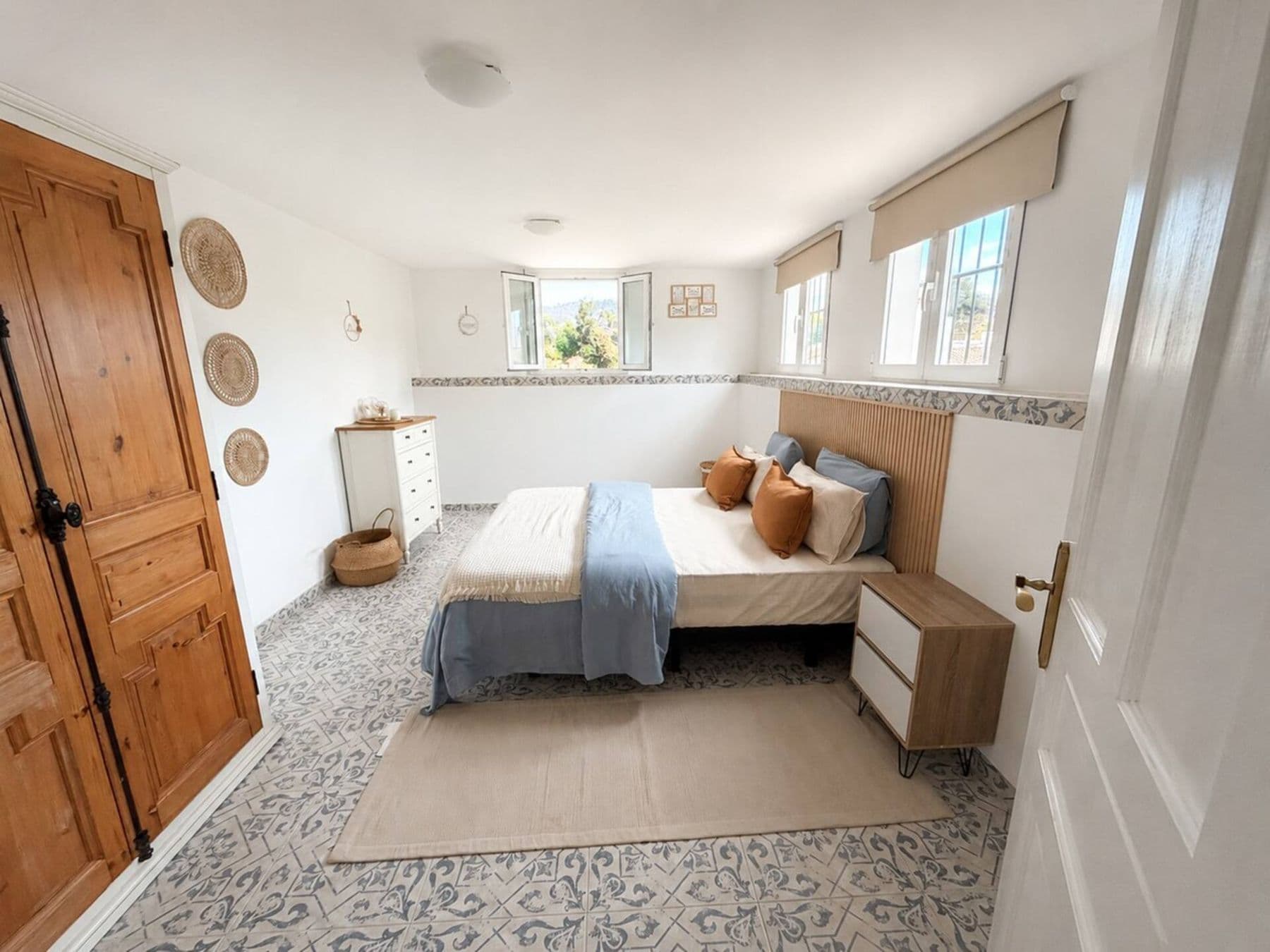 Bright bedroom with double bed, wooden headboard and windows onto greenery